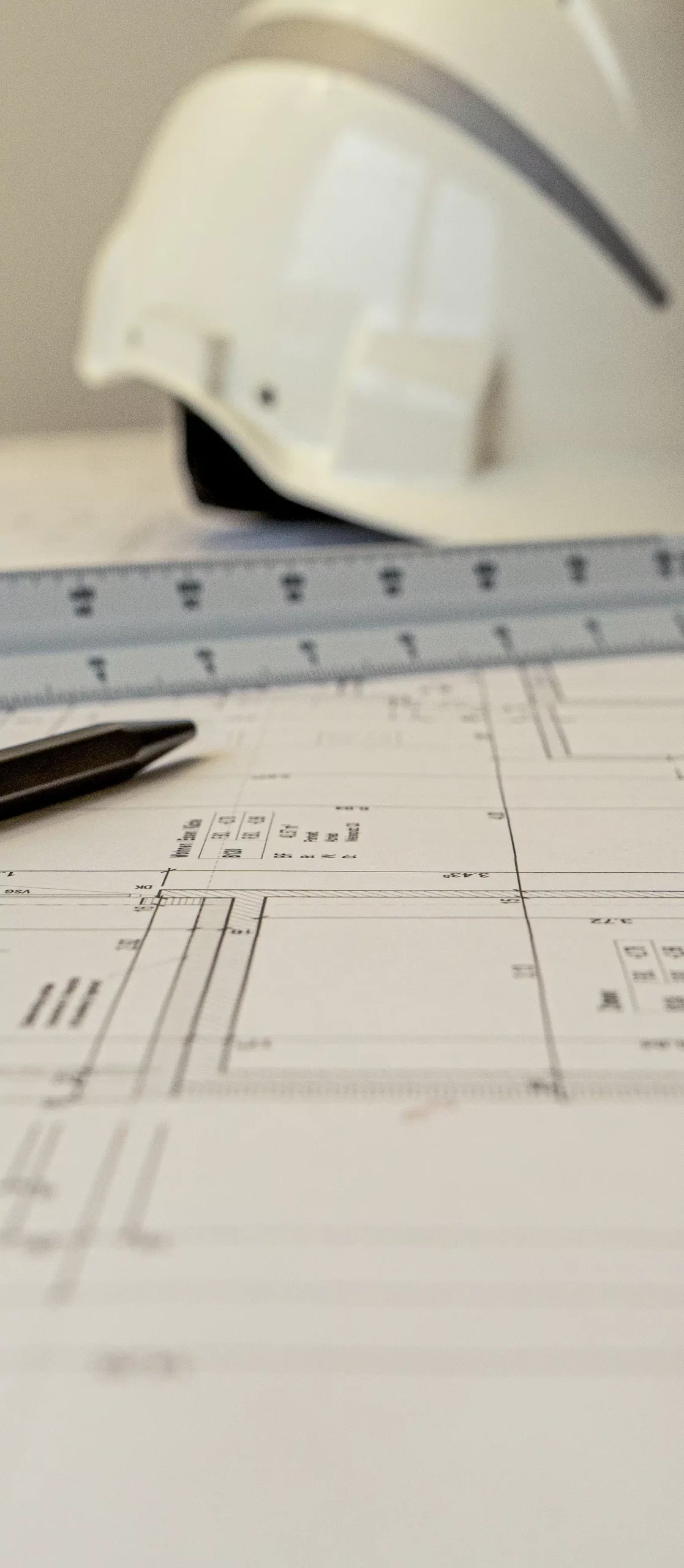 Bauplan mit Helm, Lineal und Stift als Symbol für professionelle Bauherrenberatung